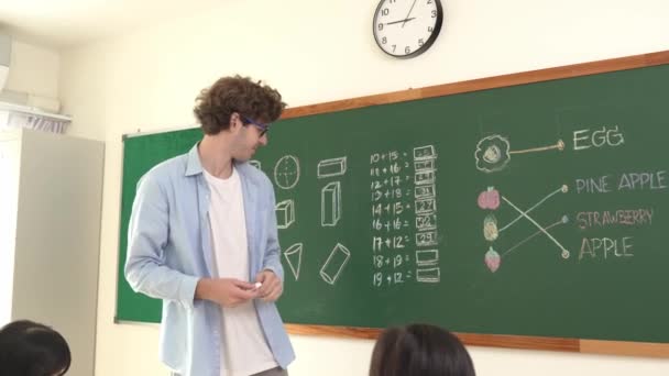 コーカサス教師が教室で数学理論について話し 学生を見ながら説明します ボードの前に立っている間 スマートな熟練したインストラクターの指導とブラックボードを指す ペダゴロジー — ストック動画