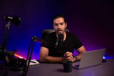 Yayıncı, fanclub dinleyicisiyle mikrofon kullanarak konuşuyor. Mor neon ışıklı modern stüdyoda yaratıcı olumlu düşünce konseptiyle canlı yayında finansal sorunları tartışıyor. Tahmin et..