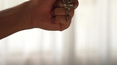 Hristiyan katolik takipçilerle dinsel bağlılık ve maneviyat duygusu doludur. Ağır çekimde el, güçlü bir kararlılıkla dini dua için kutsal haçı tutar. Filizlenen