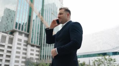 Yetenekli bir iş adamı pazarlama ekibiyle pazarlama stratejisi hakkında konuşurken gökdelende dururken telefon kullanıyor. Mutlu yönetici, modern kentsel şehirdeki satışları arttırmak için meslektaşını arıyor. Urbane.