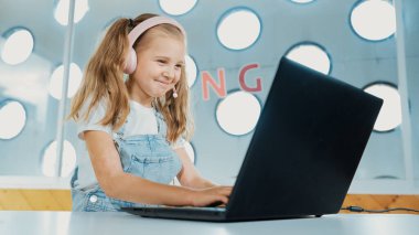 Dizüstü bilgisayarda çalışan ya da online sınıfta okuyan genç bir öğrenci. Ev ödevi yaparken ya da müzik dinlerken bilgisayarda yazan beyaz bir kız. Kulaklık takan küçük bir çocuk. Yaratıcı öğrenme. Etkinlik.