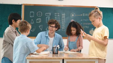 Zeki öğretmen, çeşitli çocuklar sınıf çalışması yapmak için birlikte çalışırken farklı çocukların zihin haritası çizdiği fikri açıklıyor. Çekici eğitmen öğretmek ve çalışmak hakkında konuşmak. Pedagoji.
