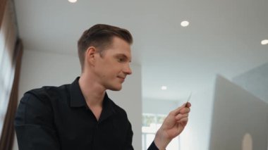 Genç adam internet bankacılığı için kredi kartlı dizüstü bilgisayar kullanıyor. İnternet üzerinden alışveriş yapıyor. Banka kartıyla modern ve kullanışlı online satın alma. Düzenle