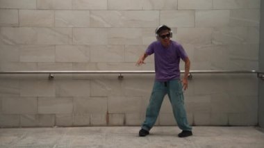 Yakışıklı hippi dans ederken müzik dinler ya da dans ederken dans eder. Çekici bir sokak dansçısı B-boy ayak sesleri çıkarıyor. Serbest dans konsepti. Yaşam tarzı. Açık hava sporu 2024. Yumuşak bir şekilde..
