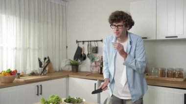 Mutlu baba yemek pişirirken müziğe geçiyor ve modern mutfakta öğle yemeği hazırlıyor. Aktif baba, sebze ve mutfak gereçleri ile çevrili sağlıklı yemek ya da salata yaparken şarkıyla dans ediyor. Pedagoji.