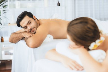 Lüks spa salonlarında sıcak mum ışığında cilt bakımı gören mutlu çift müşterisi. Sağlık kaplıcasında güzellik tedavisiyle tuz temizliği. Sessiz.