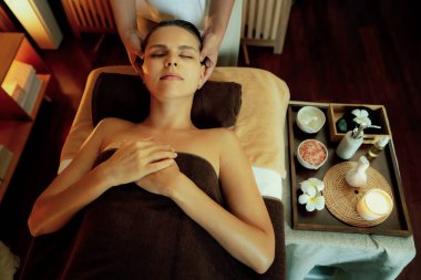 Beyaz kadın stres önleyici kafa masajı yapmaktan ve lüks otel veya otelde sıcak mum ışığında yüz güzelliği eğlencesi yapmaktan zevk alıyor. Sessiz.