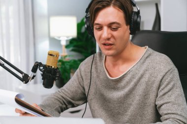 Akıllı yayıncının sunucu kanalı canlı sosyal medya yayını ile dinleyicilere senaryo okuyarak, kulaklık takarak modern ev stüdyosundaki video flamalarını kaydediyor. Bireysel.