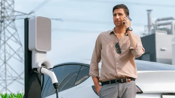 Man Talking Phone While Recharge Car Battery Charging Station Connected — Stock Photo, Image