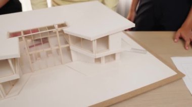 Mimari ekipman kullanarak yavaş çekim ev tasarımcısı bir plan çizerken, iç mimari tasarımcı da müşterilerin talebine göre renk örneklerinden uygun renkler seçiyor. Değiştirilmiş