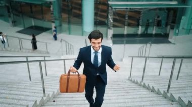 Terfi alma, satışları artırma, maaşları artırma konusunda iyi haberleri kutlamak için dans eden mutlu iş adamı şehirde geçmişi bulanık bir şekilde merdivenlerden çıkarken. Neşeli bir ruh hali. Sevinçli..