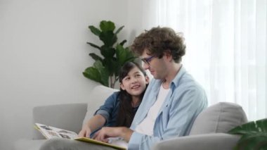 Beyaz bir baba ve tatlı bir kız kanepede otururken masal kitabı okuyorlar. Mutlu bir baba, sevimli bir Amerikan çocuğuna, birlikte zaman geçirirken hayal gücünün gelişmesi için hikaye anlatıyor. Pedagoji.