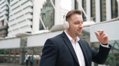 Mutlu iş adamı kulaklık takıyor, müzik dinliyor ve şehir merkezinde canlı bir şekilde yürürken müzik eşliğinde hareket ediyor. Menajer kulaklık takar ve gevşetici kafiyelerin keyfini çıkarır. Urbane.