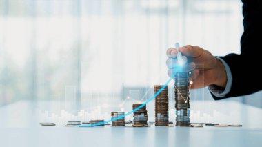 Dijital grafik göstergeli bozuk para yığını iş yatırımını ve ekonomik büyümeyi sembolize ediyor. Finansal hedefe ulaşmak ve kâr sağlamak için finansal planlama yapan bir iş adamı. Kurnaz.