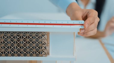 Profesyonel mimar erkek mühendisin yakın çekim görüntüsü modern ofisteki ev modelini ölçmek için cetvel kullanır. Yaratıcı yaşam ve tasarım konsepti. Geçmişi bulanıklaştırıyor. Eline odaklan. Tertemiz.