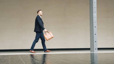 İş adamlarının bavul tutarken ve şehir merkezindeki iş yerine yürürken yan görüntüsü. Profesyonel proje yöneticisi dışarıda resmi takım elbise giyerken toplantıya gidiyor. Urbane.