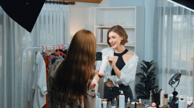 Etkilenen iki ortak canlı yayında video görüntülerini çekiyor makyaj malzemesi prim sosyal medya veya blog. Kozmetik stüdyosu ışıklandırmalı mutlu genç kız çevrimiçi pazarlama oturumu yayını için..