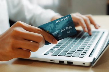 Genç adam, laptop bilgisayar başvurusu ya da web sitesinde online alışveriş yapmak için kredi kartı kullanıyor. E-ticaret ve online alışveriş konsepti. uds