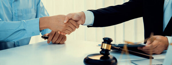 Businessman and corporate lawyer make successful deal with handshake in law firm office. Attorney and client achieving legal consultation and celebrating mutually beneficial partnership.Panorama Rigid
