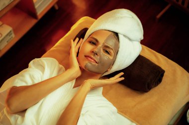 Kaplıca salonunun sakin atmosferi, üst düzey kadın müşteri sıcak mum ışığında kömür kömürü yüz kremi masajıyla kendini yenilemeye çalışıyor. Yüz bakımı ve güzellik konsepti. Sessiz.