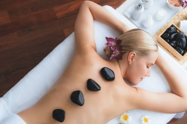 Lüks tatil beldesindeki kaplıca salonunda sıcak taş masajı. Gündüz huzurlu ortam, mutlu kadın müşteri bazalt taşı masajının keyfini çıkarıyor. Sessiz.