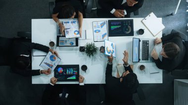 Çeşitli pazarlama ekipleri iş toplantısına hazırlanıyor. İş adamlarının yukarıdan aşağıya havadan görüşü masaya dizilmiş dizüstü bilgisayar ve tablet ile mali istatistikler. Yaratıcı iş. Müdürlük.