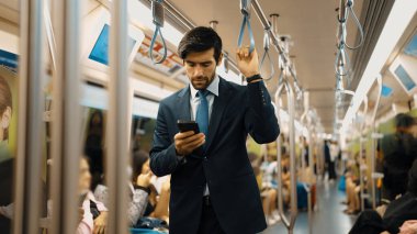 Trende insanlarla çevrili dururken telefona bakan profesyonel bir iş adamı. Kafkas proje yöneticisi e-postaları kontrol ediyor, arka planı bulanık pazarlama stratejisi planlıyor. Sevinçli..