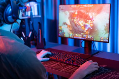 Savaş arenasında çoklu oyunlar takımıyla Moba 'da savaşan genç oyun flamasının sunucu kanalı, neon dijital ışık modern odasındaki arka görüntü ile bilgisayar monitöründe kulaklık takıyor. Toplayıcı.