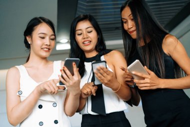 Üç kadın arkadaş ellerinde cep telefonuyla sohbet ediyorlar. Sosyal medya, dedikodu haberleri ve online alışveriş kavramı. uds