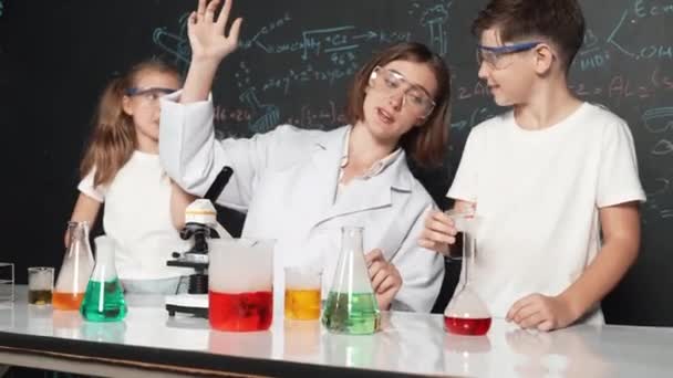 Kaukasischer Junge Mischt Chemische Flüssigkeit Während Der Lehrer Ratschläge Gibt — Stockvideo
