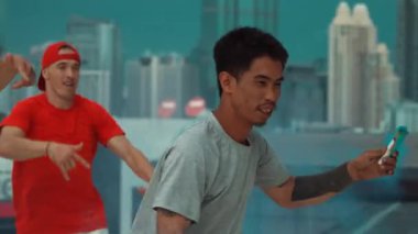 Bir grup çok kültürlü hippi çatıda işaret fişeği çalıyor. Zenci dumanı tutan çekici bir sokak dansçısı hip-hop müzik eşliğinde break dans yapıyor. Açık hava sporu 2024. Sokak dansı. hiphop.