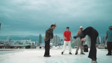 İspanyol hipster dansları şehrin mavi gökyüzü manzaralı çok kültürlü arkadaşlarıyla çevrili. Çatıda bir grup sokak dansçısı sahne alıyor. Aktif, eğlenceli, mutlu atmosfer. Açık hava sporu 2024 hiphop..