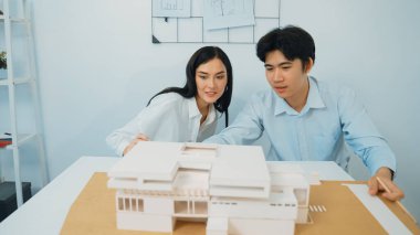 Becerikli mimari mühendisi ekip ölçümü ve ev modeline birlikte çalışırken karar verme ve toplantı odasındaki bina yapısı ve planlarla ilgili tartışmalar. Tertemiz..