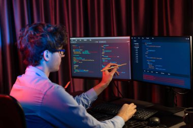 Uygulama pc ekranları ile çevrili çevrimiçi yazılım geliştirme bilgilerini yoğunlaştıran IT geliştiricisi, neon modern ofis evindeki web sitesinde yazılım için program yaratıyor. Toplayıcı.