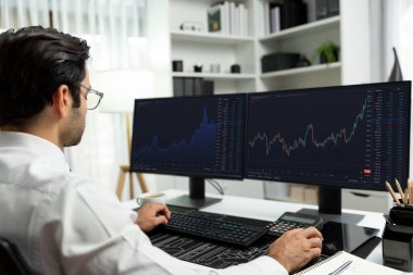 Akıllı tüccar işadamı, modern merkez ofisindeki araştırma pazarında en yüksek kârlı finansal teknolojiye yatırım yaparak bilgisayar üzerinde iki dinamik borsa yatırım ekranını analiz ediyor. Tahmin et..