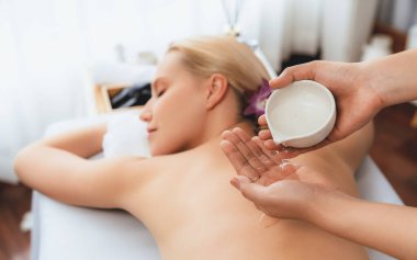 Masör elleri kadının sırtına aroma yağı döküyor. Masözler lüks otellerdeki kaplıca salonundaki müşteriler için yağ masajı prosedürü hazırlıyorlar. Aroma yağı vücut masajı konsepti. Sessiz.