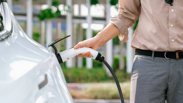 남자는 주차장에 충전소에서 자동차 배터리를 충전기 가능한 친화적 여행을위한 충전식 — 스톡 사진
