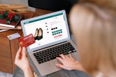 Genç bir kadın internet bankacılığı için kredi kartıyla dizüstü bilgisayar kullanıyor. Evinde online ödeme kapısı ile E ticareti yapıyor. Banka kartıyla modern ve kullanışlı online alışveriş. Blithe