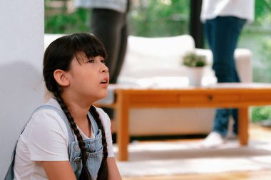 Stresli ve mutsuz genç kız arka planda ebeveynleri tartışırken köşede ağlayıp üzülüyor. Evde aile içi şiddet ve travmatik çocukluk depresyona dönüşür. Eşzamanlama