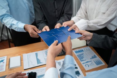 Şirket çalışanı, yapboz parçalarını masa üzerindeki raporlara ortaklık ve takım çalışması olarak bağlıyor. Yapboz 'u birleştirerek iş dünyasındaki birlik ve sinerji. Uyum