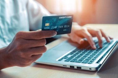 Genç adam, laptop bilgisayar başvurusu ya da web sitesinde online alışveriş yapmak için kredi kartı kullanıyor. E-ticaret ve online alışveriş konsepti. uds