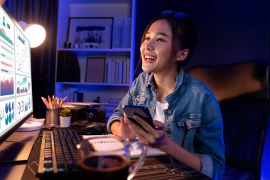 Gülümseyen genç, güzel Asyalı yaratıcı satış hedefi raporunun kar tablosuna bakıyor ve notlar üzerine notlar yazarak neon ışığı gecesinde yeni bir strateji pazarı projesine yatırım yapmayı planlıyor. Taktik.