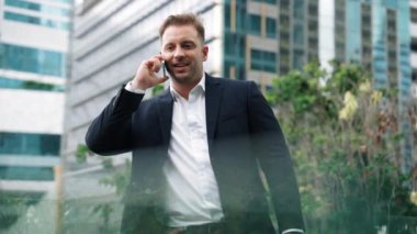 Başarılı bir iş adamı, pazarlama ekibiyle telefon kullanarak yatırım hakkında konuşurken çatıda duruyor. Kafkasyalı yatırımcı modern gökdelen manzarasına bakarak rahatlamanın keyfini çıkarıyor. Yaşam tarzı. Urbane