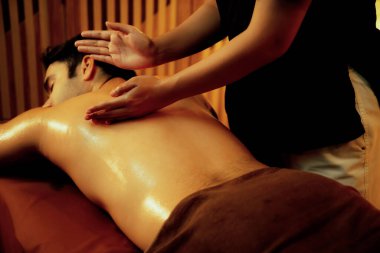Beyaz erkek müşteri stres önleyici spa masajının keyfini çıkarıyor ve lüks otel ya da oteldeki ortam kaplıcalarında sıcak mum ışığında güzellik teniyle eğleniyor. Sessiz.