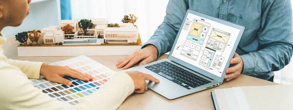 Cropped image of interior designer presents color from color swatches while laptop displayed website wireframe designs for mobiles app and website. Creative design and business concept. Variegated.