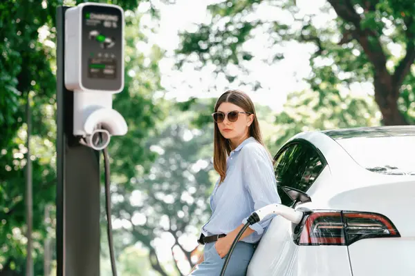道路旅行中に電気自動車の電池を充電する若い女性 自然林や国立公園でEv車 休暇や休暇中にエコフレンドリーな旅行 エクスアルト — ストック写真