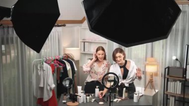 Etkilenen iki ortak canlı yayında video görüntülerini çekiyor makyaj malzemesi prim sosyal medya veya blog. Kozmetik stüdyosu ışıklandırmalı mutlu genç kız çevrimiçi pazarlama oturumu yayını için..