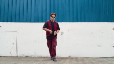 Beyaz arka planda break dans pratiği yapan yakışıklı bir sokak dansçısı. Hip hop tarzı giyinen sporcu, mavi arka planlı bir sokakta müzik eşliğinde ayak sesleri çıkarıyor. Açık hava sporu 2024 hiphop..