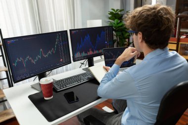 Ekranlarda dizüstü bilgisayara bakan, elinde not defteri ve kalemle panorama ofisinde gerçek zamanlı yatırım yapan, dinamik yatırım konseptini analiz eden genç bir tüccar. Toplayıcı.