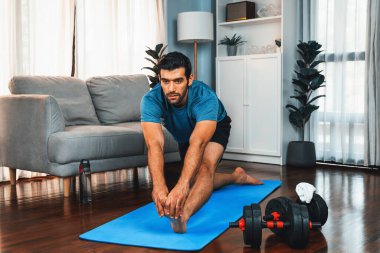 Atletik ve sporcu adam, evdeki fiziğe ve sağlıklı spor yaşam tarzına uygun vücut egzersizlerinden önce ısınıyor ve esniyor. Gaiety ev egzersizi antrenman konsepti.